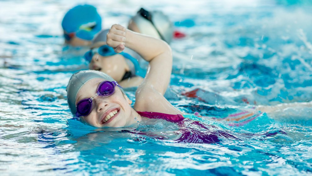 Kinder beim Schwimmunterricht. Kinder beim Schwimmunterricht, die unter Anleitung eines Trainers schwimmen und lernen.