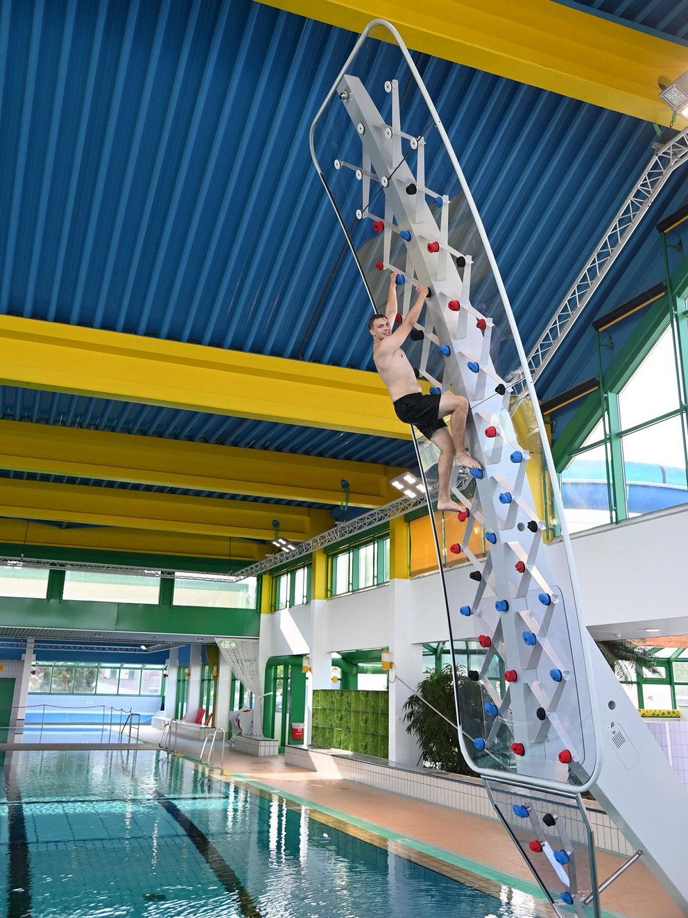 indoor-kletterwand Weitläufiges Hallenbad mit blauem Wasser mit indoor-Kletterwand, umgeben von Fliesen und Liegen, perfekt für Freizeit- und Wettkampfschwimmen.