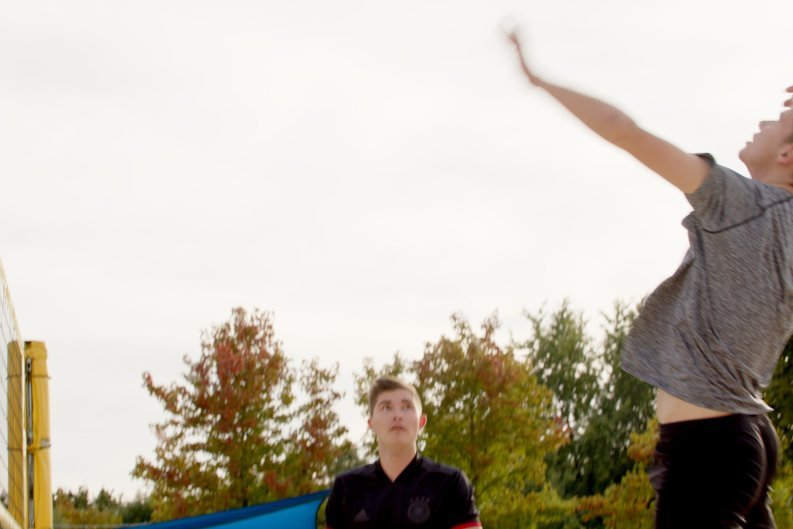 Volleyballspieler beim Sprungschlag. Ein Mann springt hoch, um einen Volleyball zu schlagen, mit einem konzentrierten Ausdruck auf seinem Gesicht.