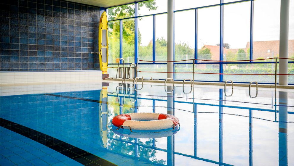 Sicher schwimmen: Hallenbad mit Rettungsring Schwimmbad im Innenbereich mit einem an der Wand befestigten Schwimmring für die Sicherheit der Nutzer