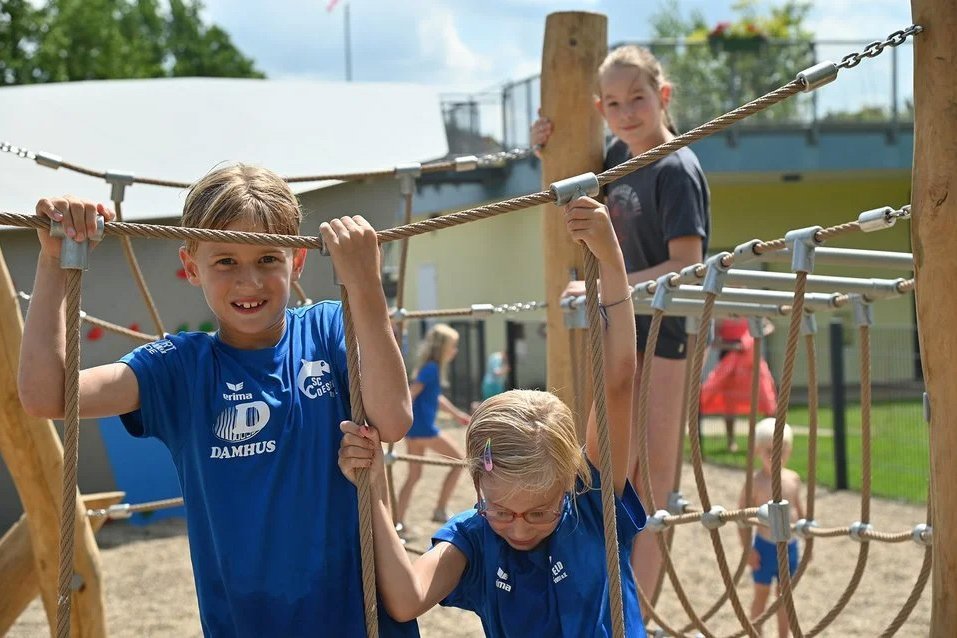 Spielende Kinder auf Kletterstruktur Kinder klettern auf einer Seilspielstruktur und haben Spaß beim Spielen im Freien.