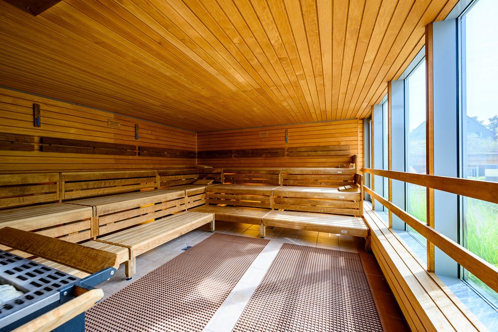 Sauna-Raum mit Holzverkleidung und Fenstern, die natürliches Licht hereinlassen.