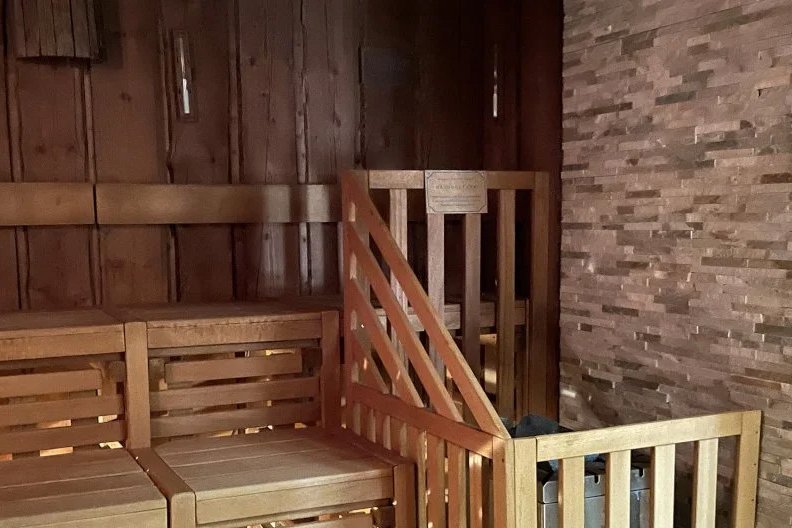 Innenansicht einer Kelosauna mit Bänken und Tür aus Holz, ideal für Entspannung und Wellness.