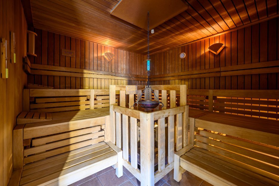 Gemütlicher Sauna-Raum, ausgestattet mit Holzbänken und sanfter Beleuchtung für eine entspannende Atmosphäre.